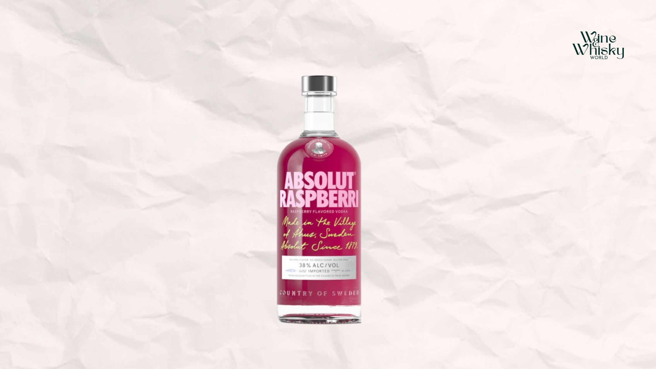 Clear glass bottle of Absolut Vodka with pink and black text on the label, reading 'Absolut ', displayed against a crumpled white paper background with the Wine Whisky World logo in the top right corner.